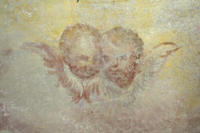 Jelovškova putta nad romanskim oknom. V obrazu putta na levi strani, ki se po obliki in obraznih potezah pomembno razlikuje od ostalih, naj bi slikar zapustil svoj avtoportret.