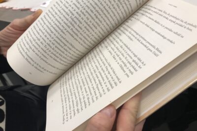 Knjigosnedka drži v roki knjigo in jo bere.