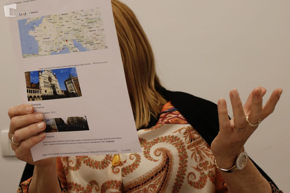 Članica bralnega krožka drži v roki list z zemljevidom in fotografijami.